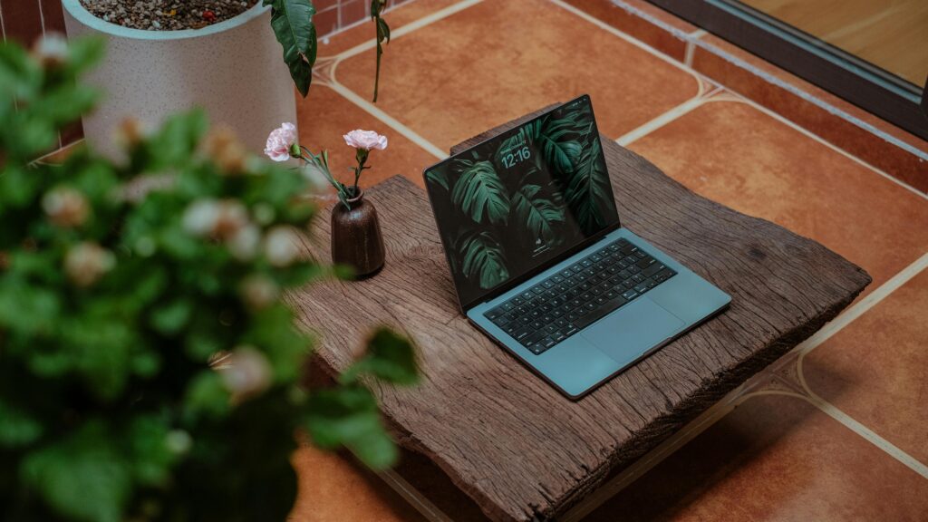 Laptop on rustic table in cozy home setting with plants, promoting productivity.